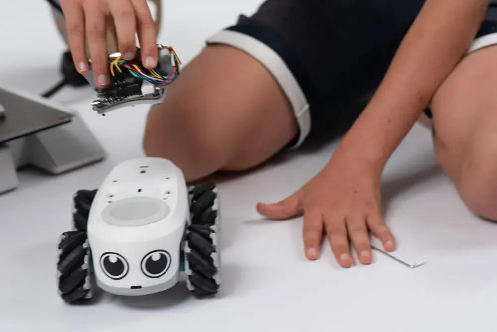 Un enfant s'amuse avec un robot ilo en explorant ses fonctionnalités avec enthousiasme.